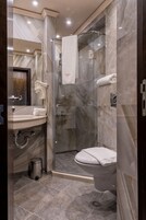 Un baño moderno con ducha de vidrio, inodoro y lavamanos con toallero.