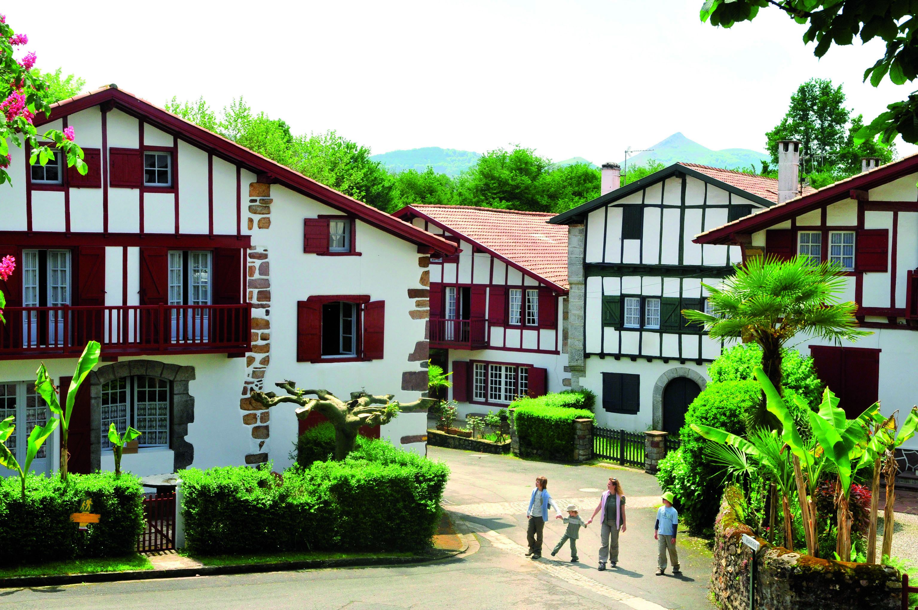 A traditional European village with timber-framed houses, a cobblestone street, and lush greenery.