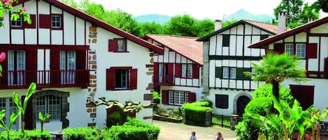 A traditional European village with timber-framed houses, a cobblestone street, and lush greenery.