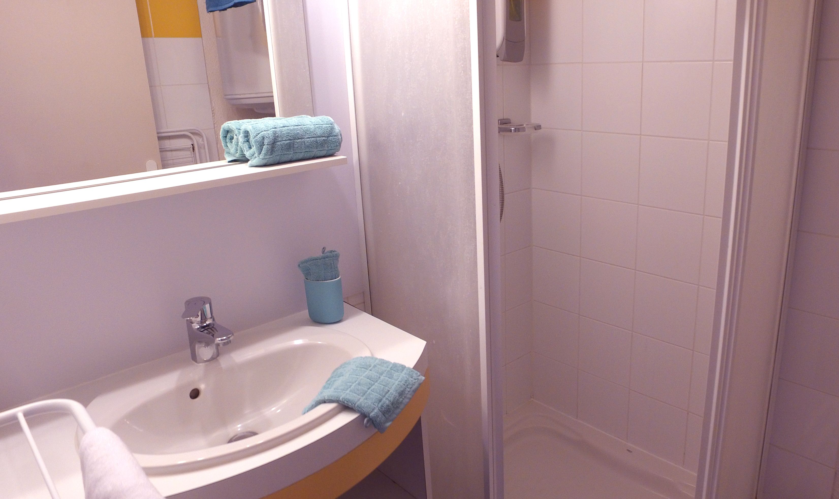 A bathroom with a sink, mirror, and a shower area.