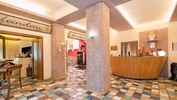 A hotel lobby with a check-in counter, a reception desk, a patterned floor, and a sign that reads "beinein".