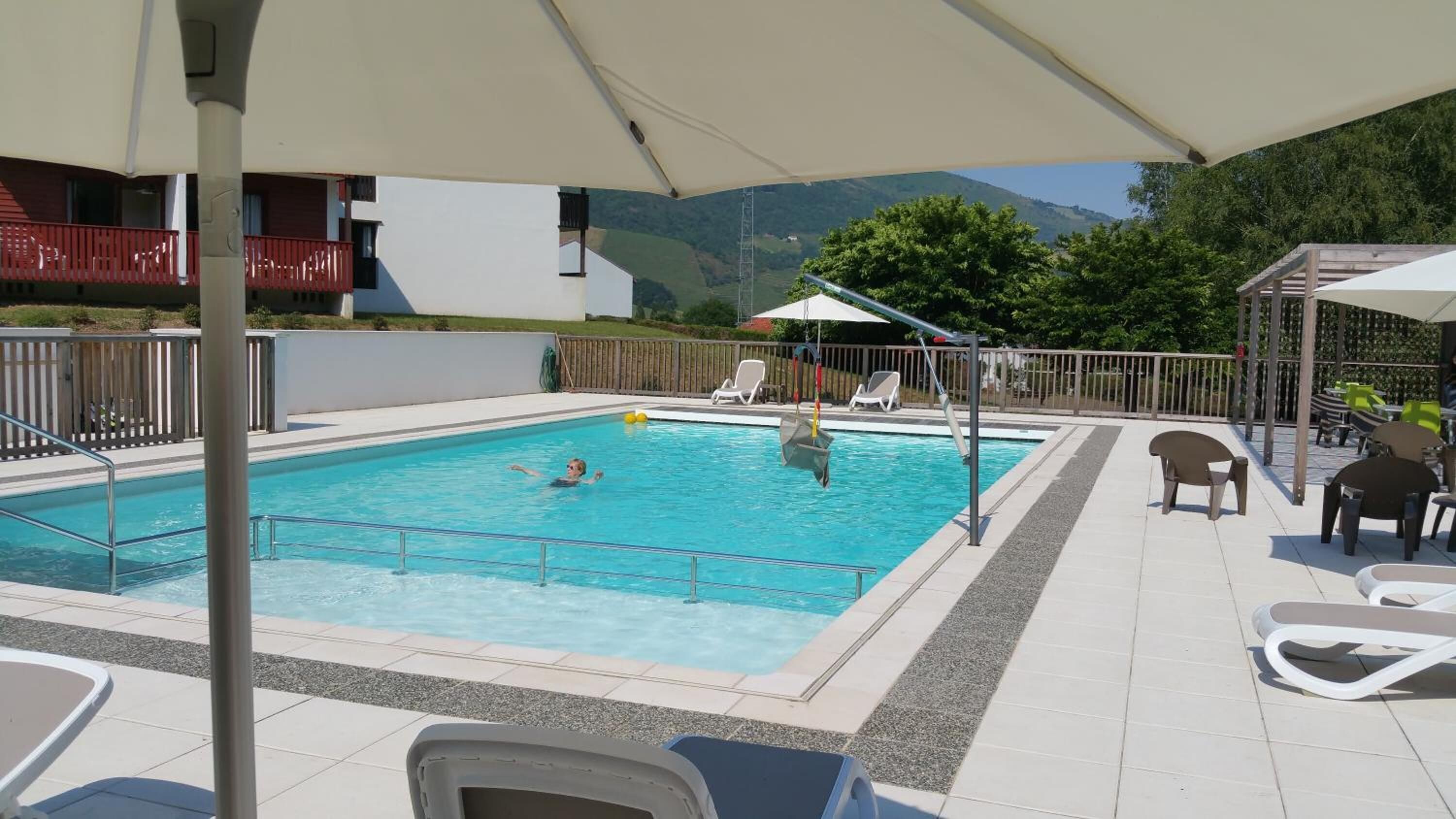 Une piscine avec vue sur des collines verdoyantes en arrière-plan.