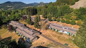A rural area with several buildings, including a long row of cabins with thatched roofs and a central building with a flat roof. - VVF Haute Loire Saint-Julien-Chapteuil (Saint-Julien-Chapteuil)