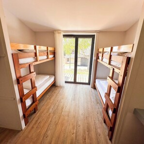 A room with two wooden bunk beds, a sliding glass door leading to an outdoor area, and a wooden floor. - VVF Haute Loire Saint-Julien-Chapteuil (Saint-Julien-Chapteuil)