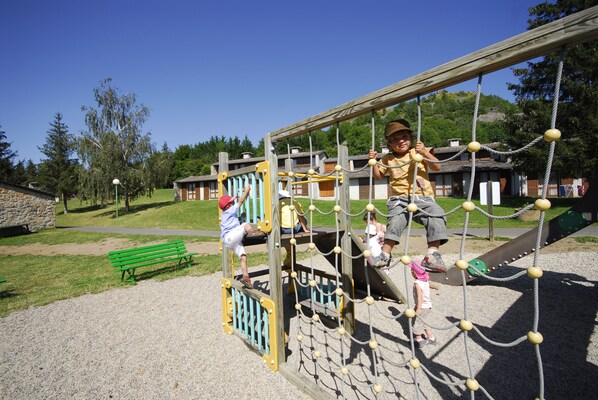 A playground with climbing structures and a green bench.