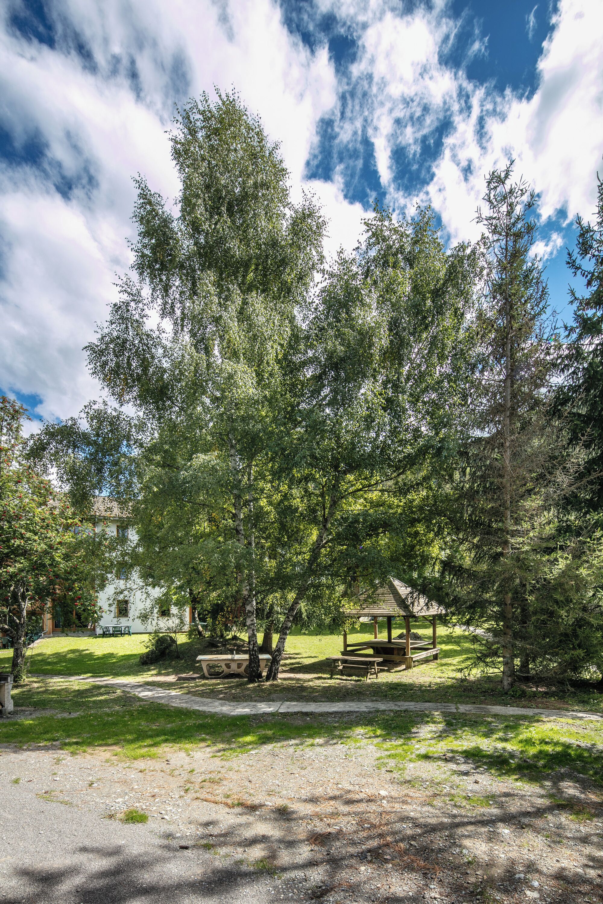 A park with picnic tables, a gazebo, and a building in the background.