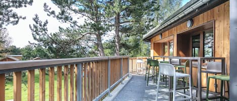 Una cabaña de madera con un porche, mobiliario exterior y vistas a árboles.