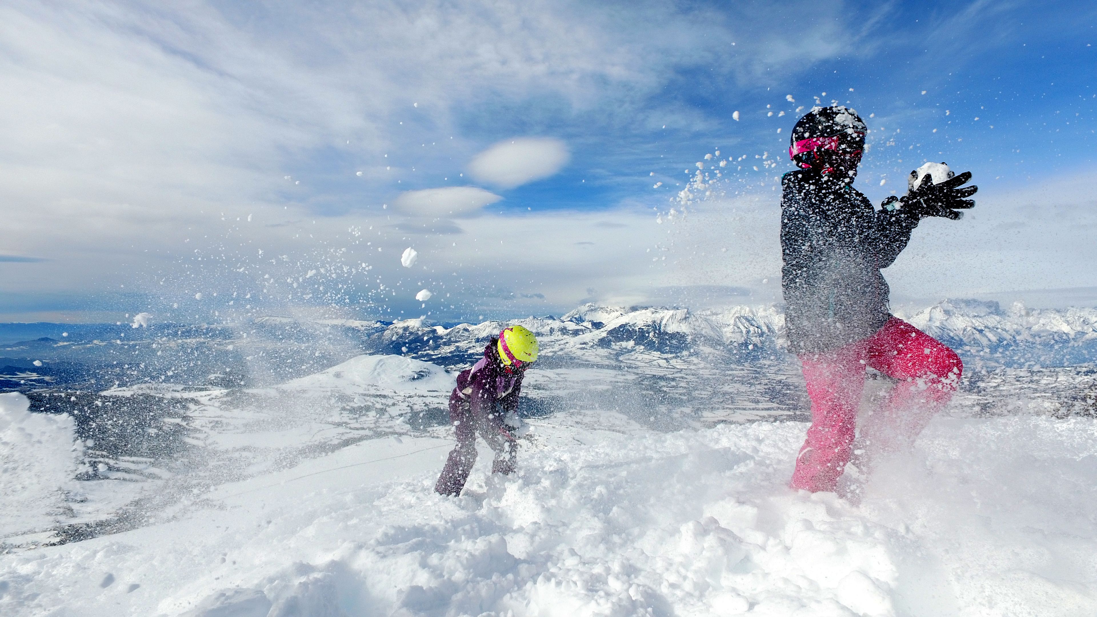 A snowy landscape with a person in a yellow helmet and pink pants.
