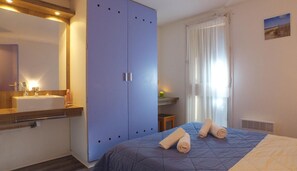 A bedroom with a bed, a wardrobe, a sink, and a mirror. - VVF Soulac-sur-Mer Bordeaux Médoc (Soulac-sur-Mer)