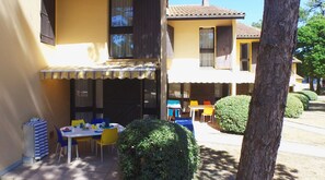 A patio with a table and chairs, a covered seating area, and a neatly trimmed bush. - VVF Soulac-sur-Mer Bordeaux Médoc (Soulac-sur-Mer)