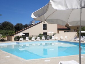 Una piscina al aire libre, sombrillas, tumbonas