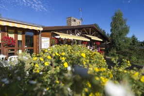 Un restaurant amb xemeneia de pedra, bigues de fusta i terrassa a l'aire lliure.