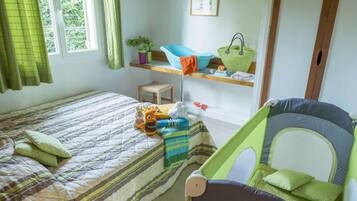 A child's room with a bed, a green playpen, and a shelf with toys and a plant.