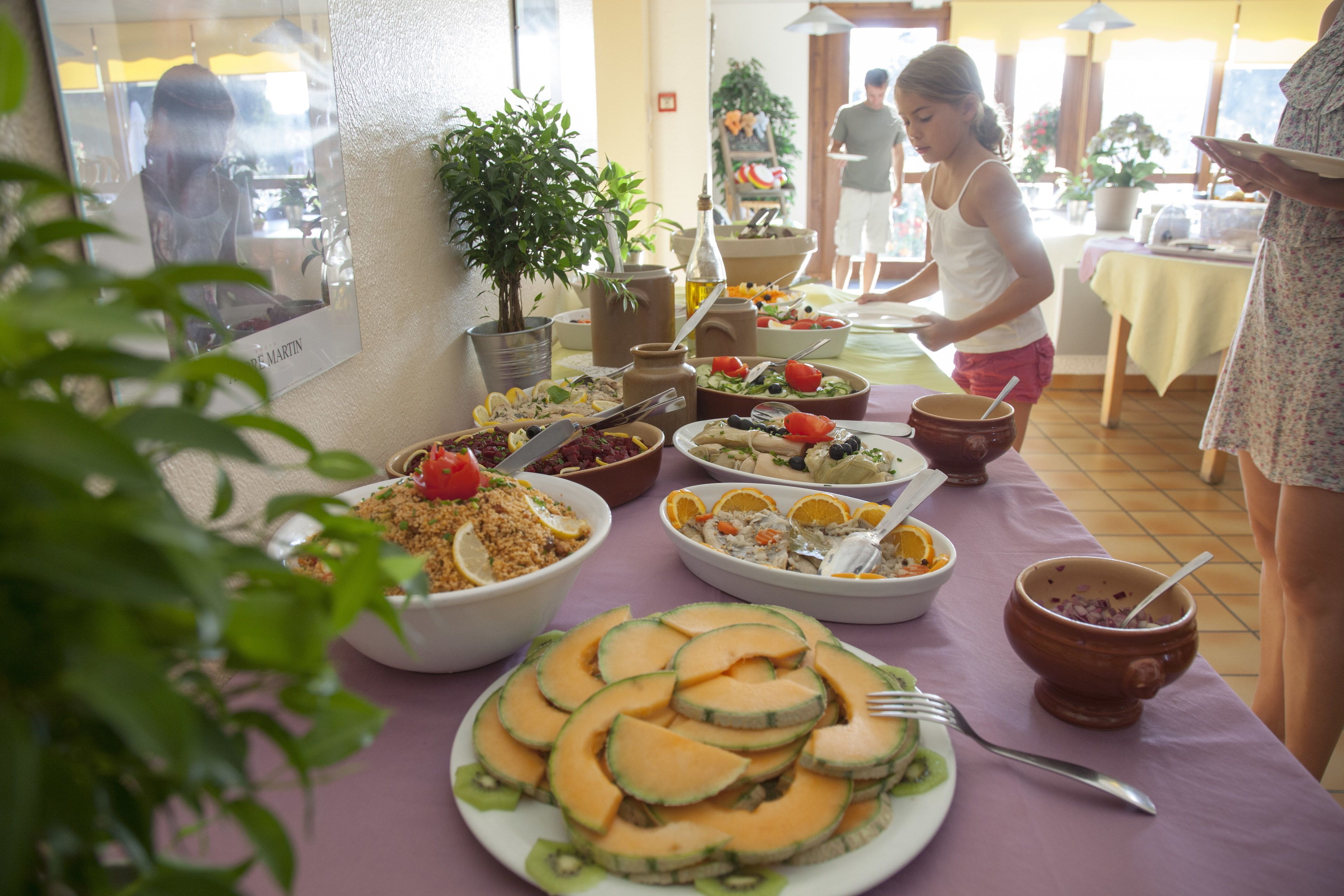 A buffet table with various dishes, including melon slices, salads, and other foods.