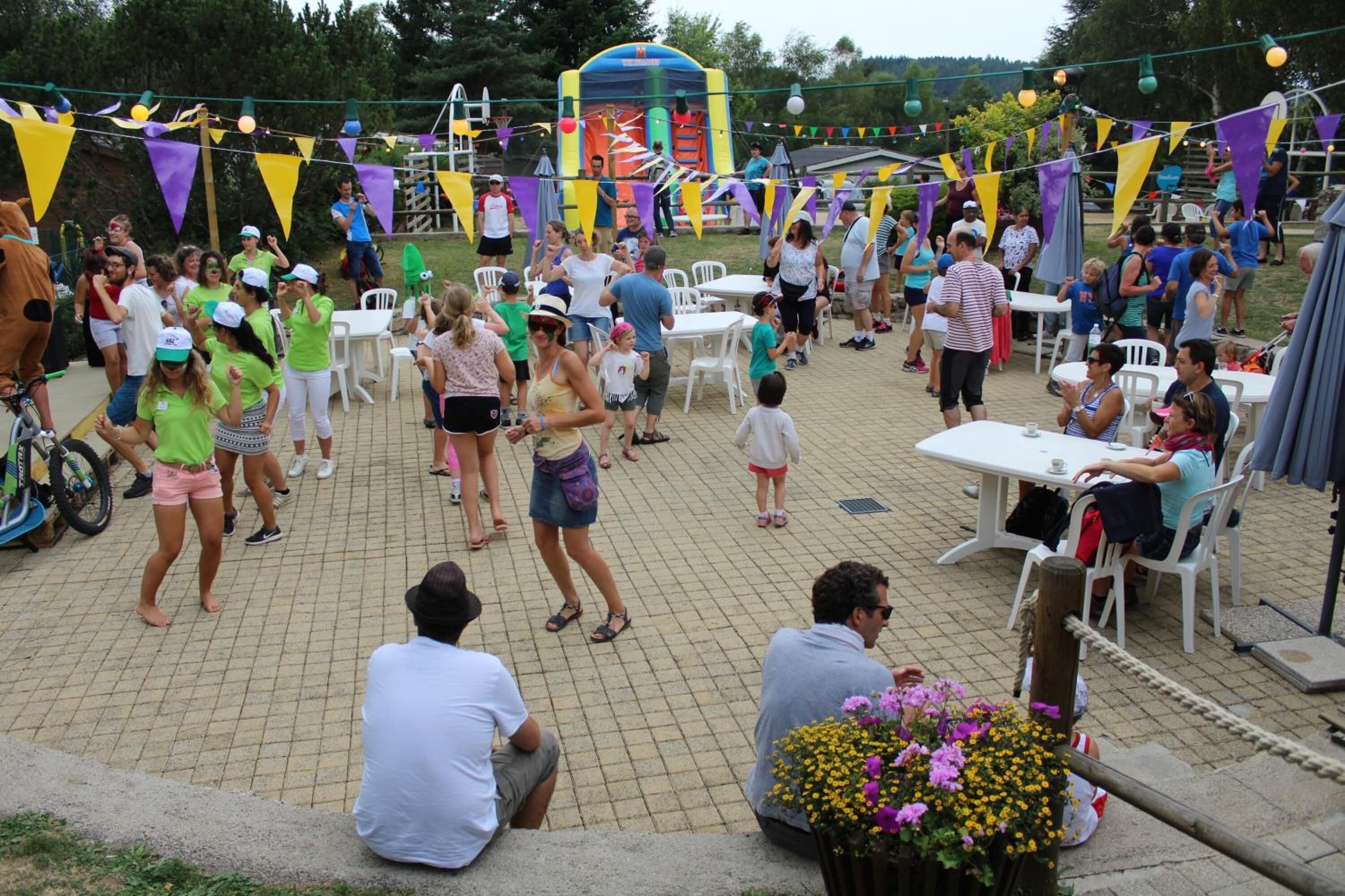 An outdoor patio area with tables and chairs, surrounded by a crowd of people.
