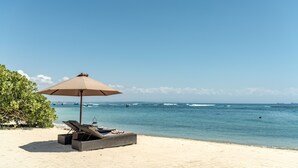 A beach with a lounge chair and an umbrella. - Kayumanis Nusa Dua Private Villa & Spa (Nusa Dua)