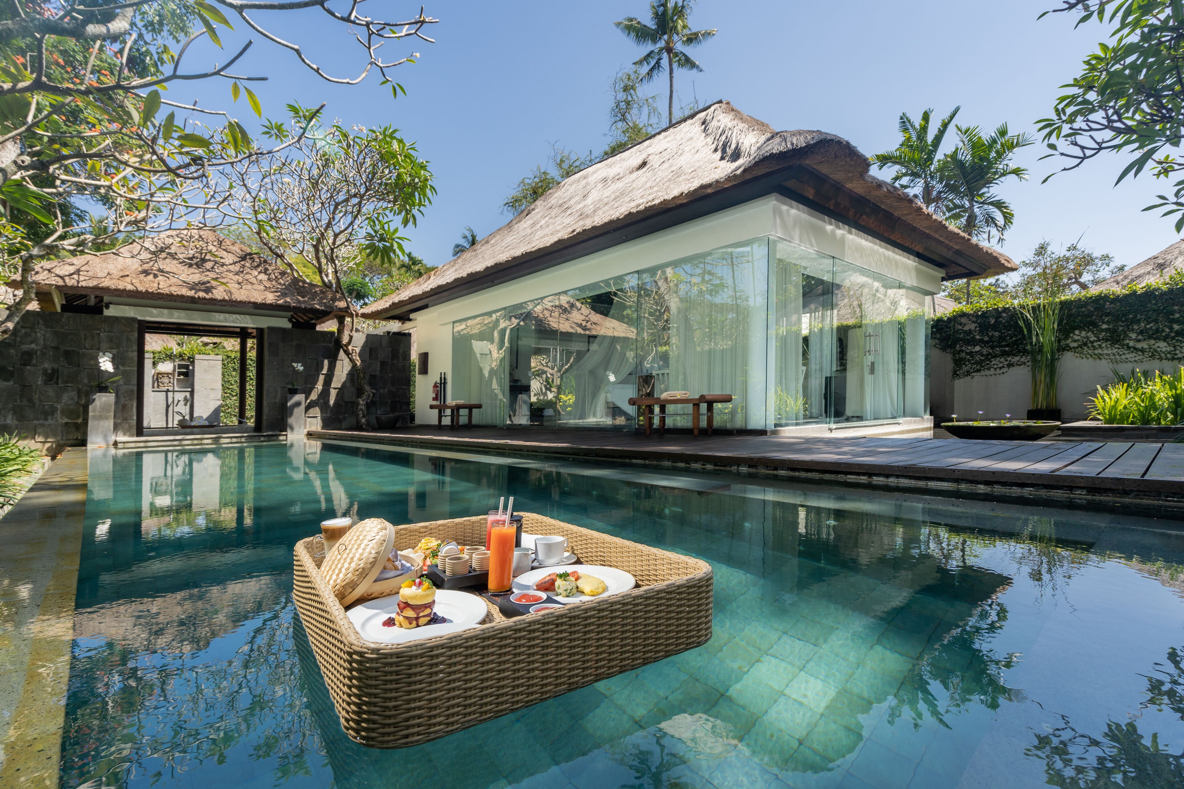 A poolside dining setup with a wicker table, plates, and a drink.