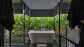 Ein modernes Badezimmer mit freistehender Badewanne, Glaswänden und Blick auf üppiges Grün.