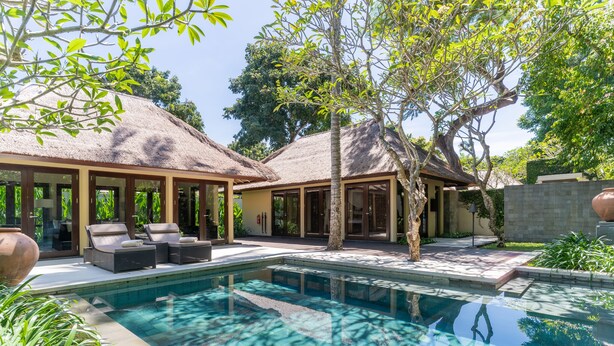 A pool area with lounge chairs and a thatched-roof building. - Kayumanis Nusa Dua Private Villa & Spa (Nusa Dua)