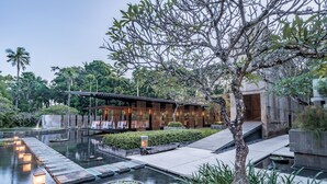 A serene outdoor area with a pool, wooden deck, and a building with a covered seating area. - Kayumanis Nusa Dua Private Villa & Spa (Nusa Dua)