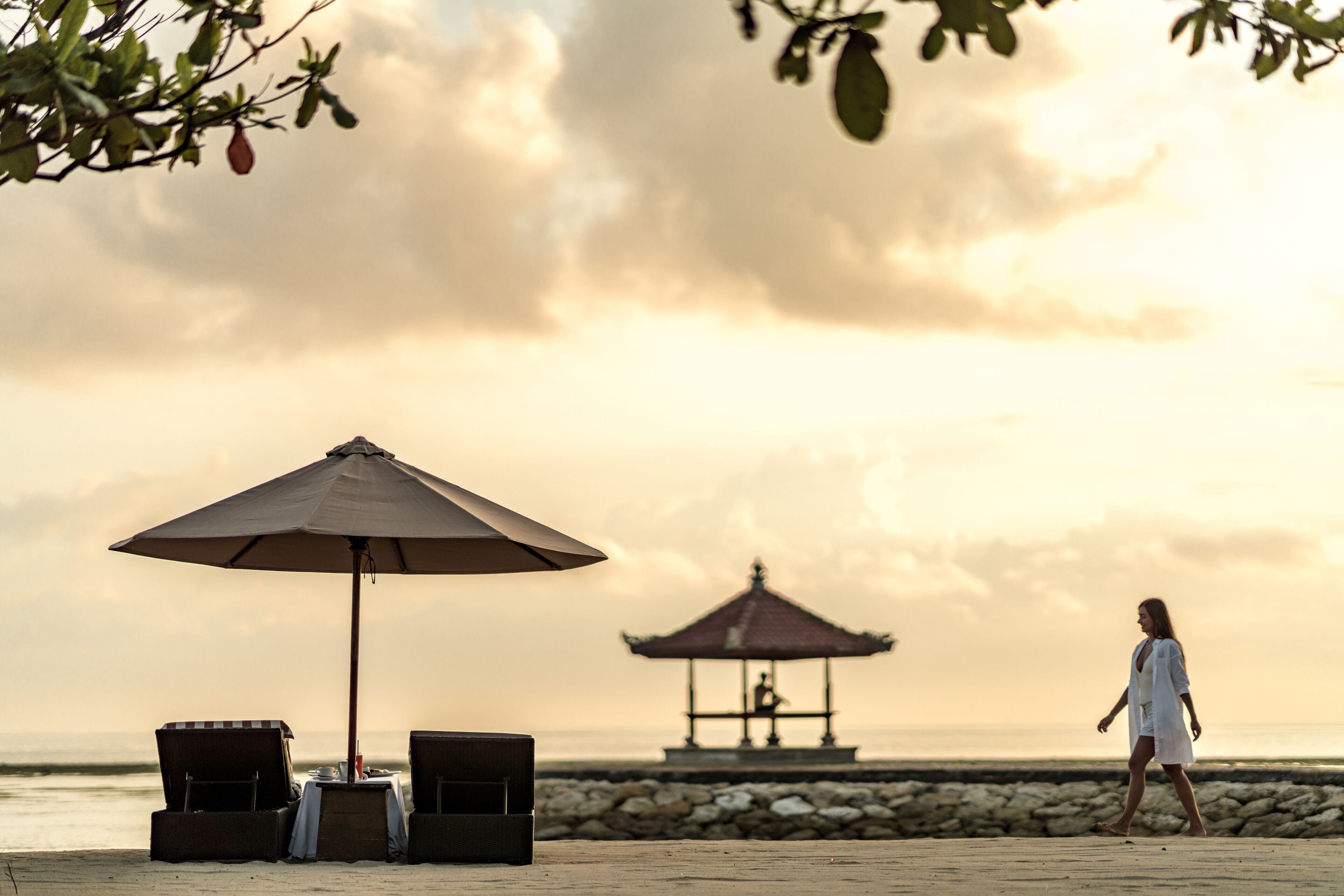 Une plage avec un kiosque, des chaises longues et un parasol.
