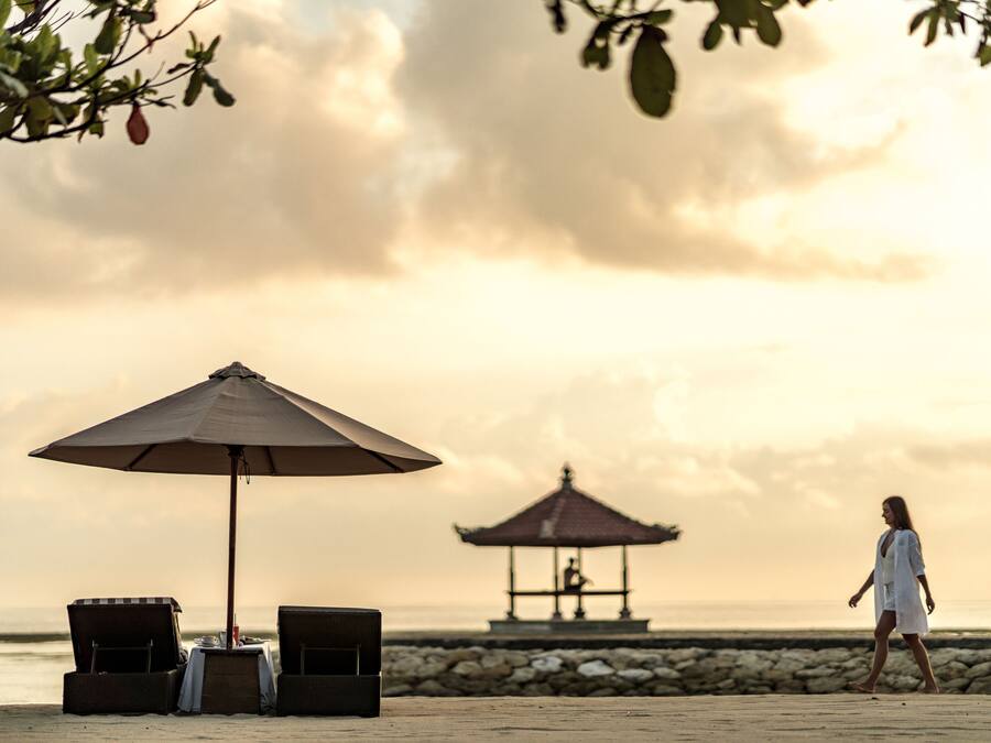 Une plage avec un kiosque, des chaises longues et un parasol.