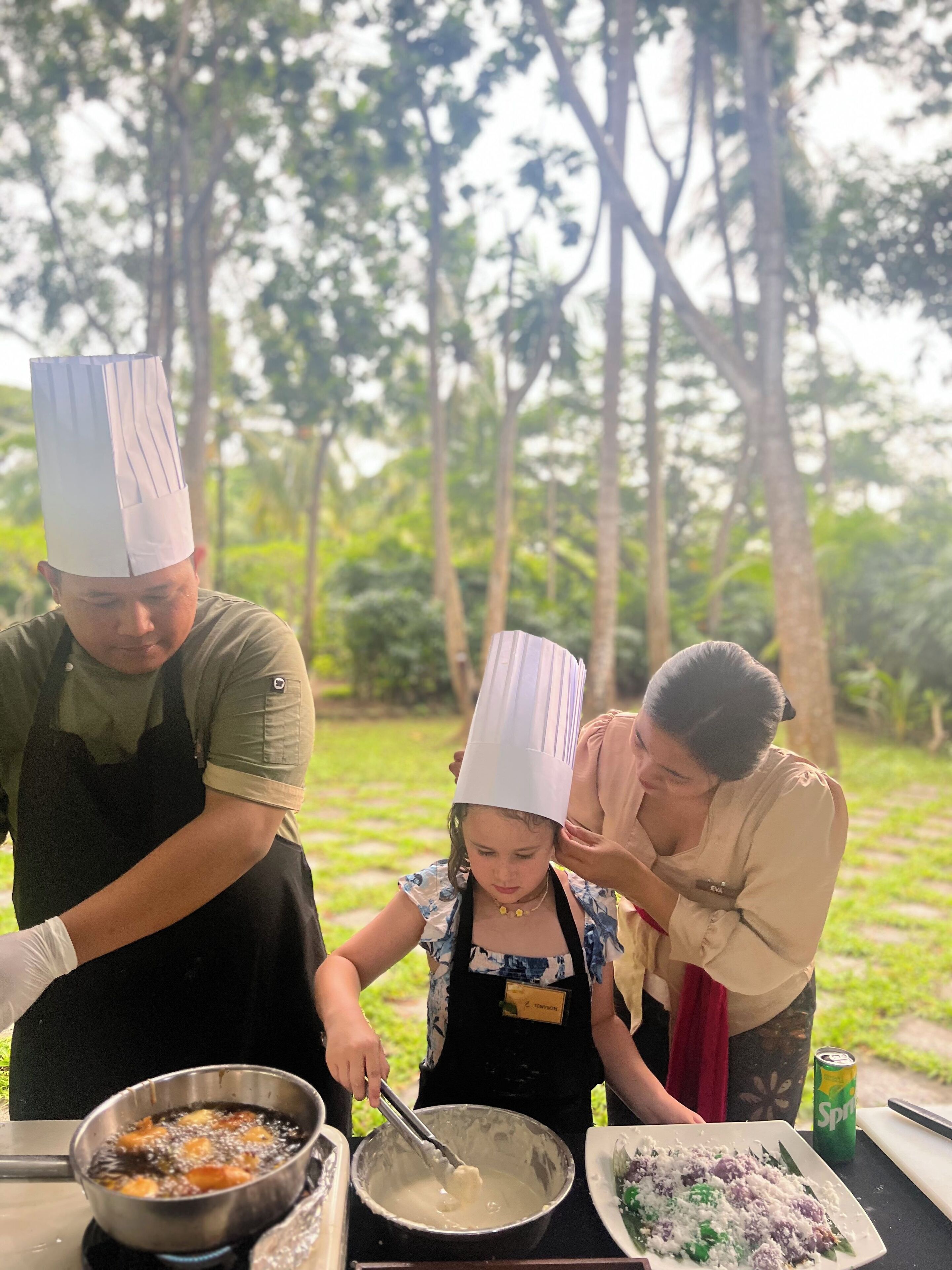 A group of people outdoors, some wearing chef hats, preparing food.