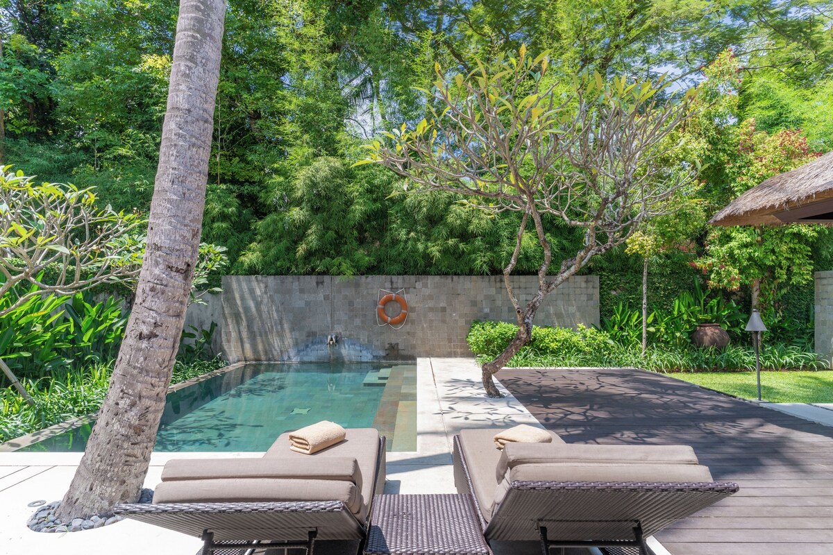 A pool area with lounge chairs, a lifebuoy, and a stone wall.