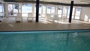 An indoor swimming pool with clear blue water, surrounded by white chairs and large windows. - VVF Jura Les Rousses, Prémanon (Premanon)