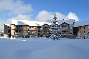 A multi-story hotel with a snow-covered roof and balconies, surrounded by snow.