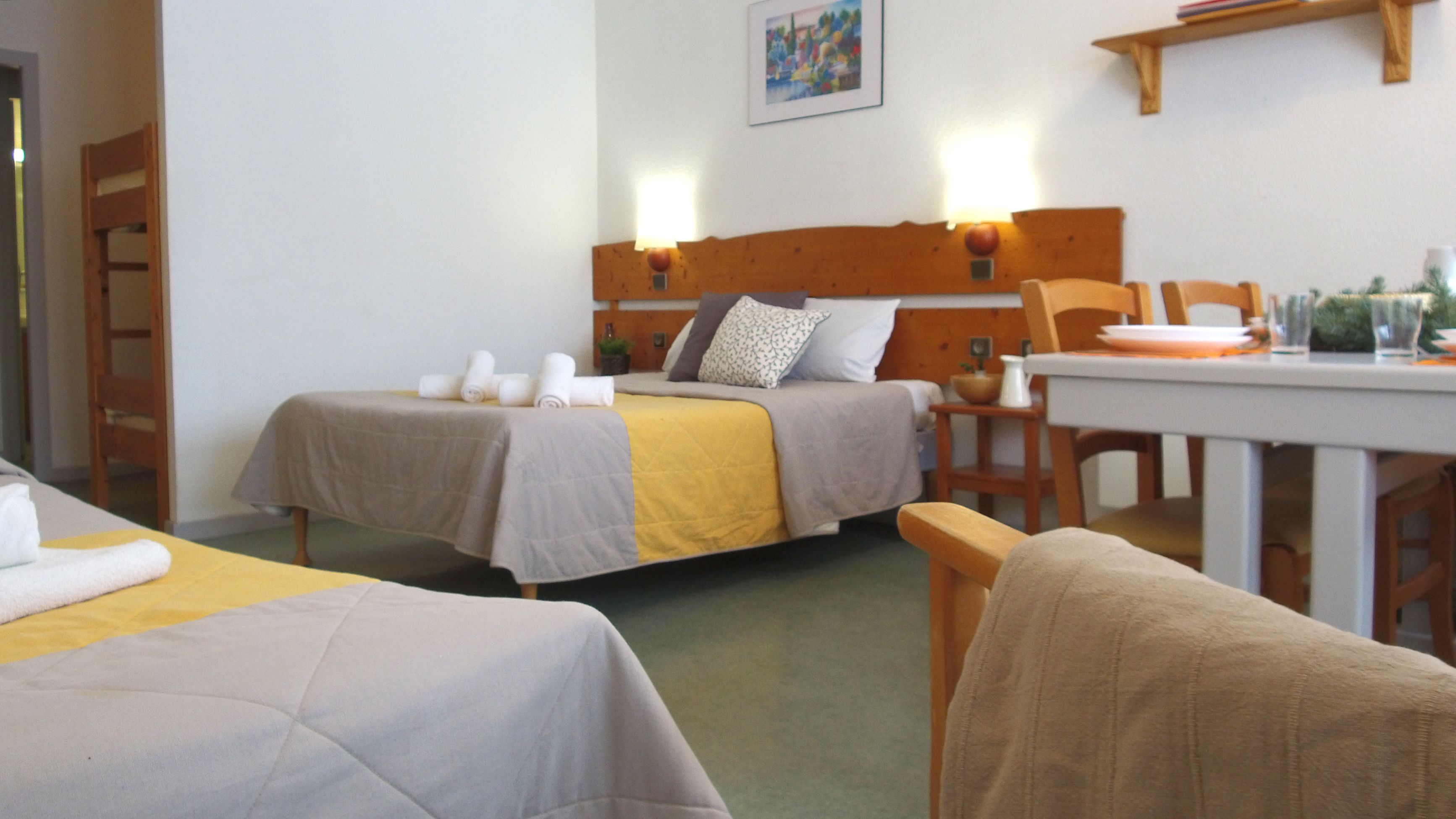 A room with two beds, a table, and a chair.