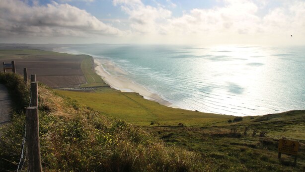 A coastal landscape with a grassy area, a fence, and a sign warning of rock fall hazard. - VVF Blériot-Plage (Sangatte)