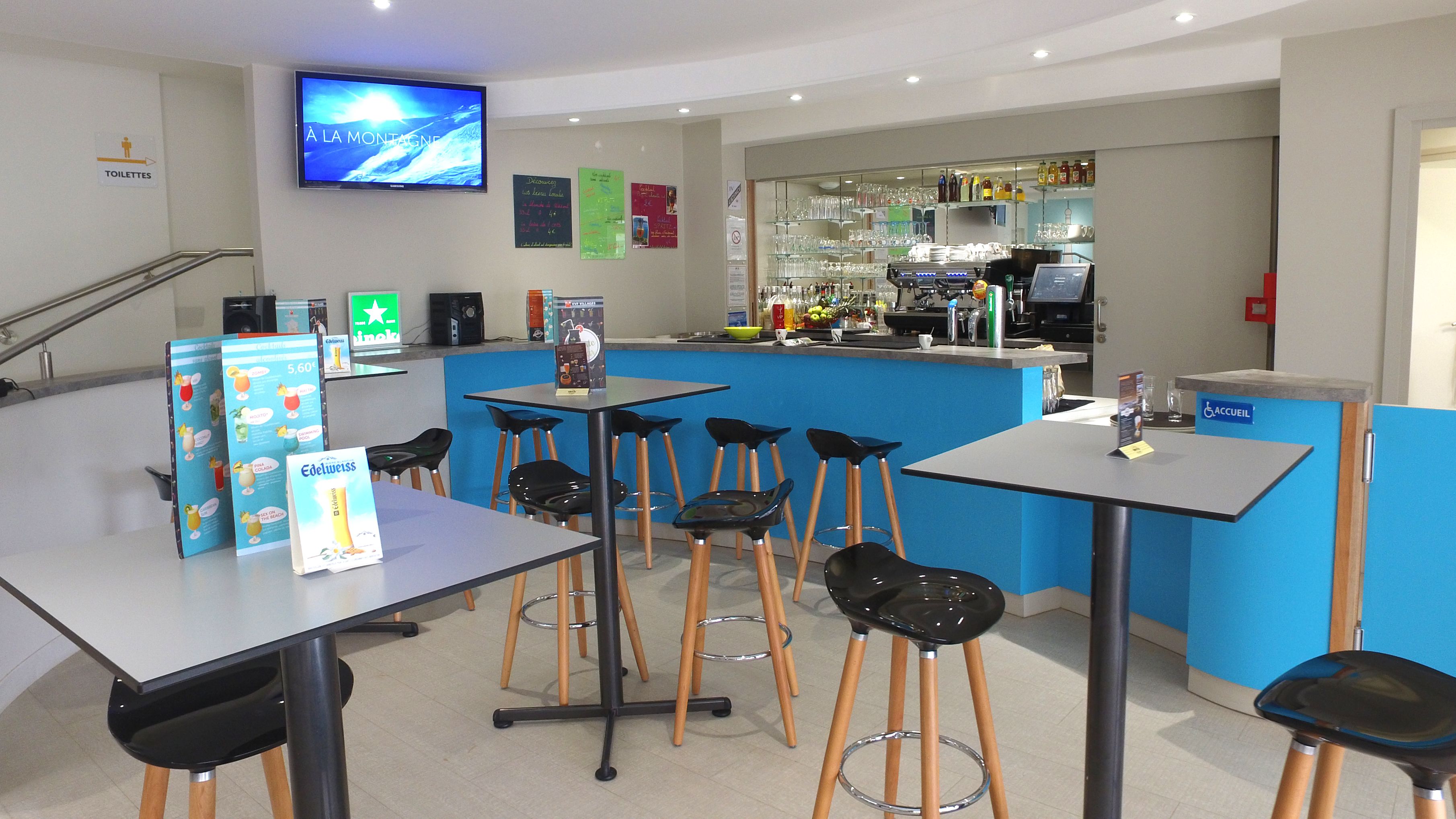 Zona de bar con taburetes, mostrador y una pantalla de televisión.