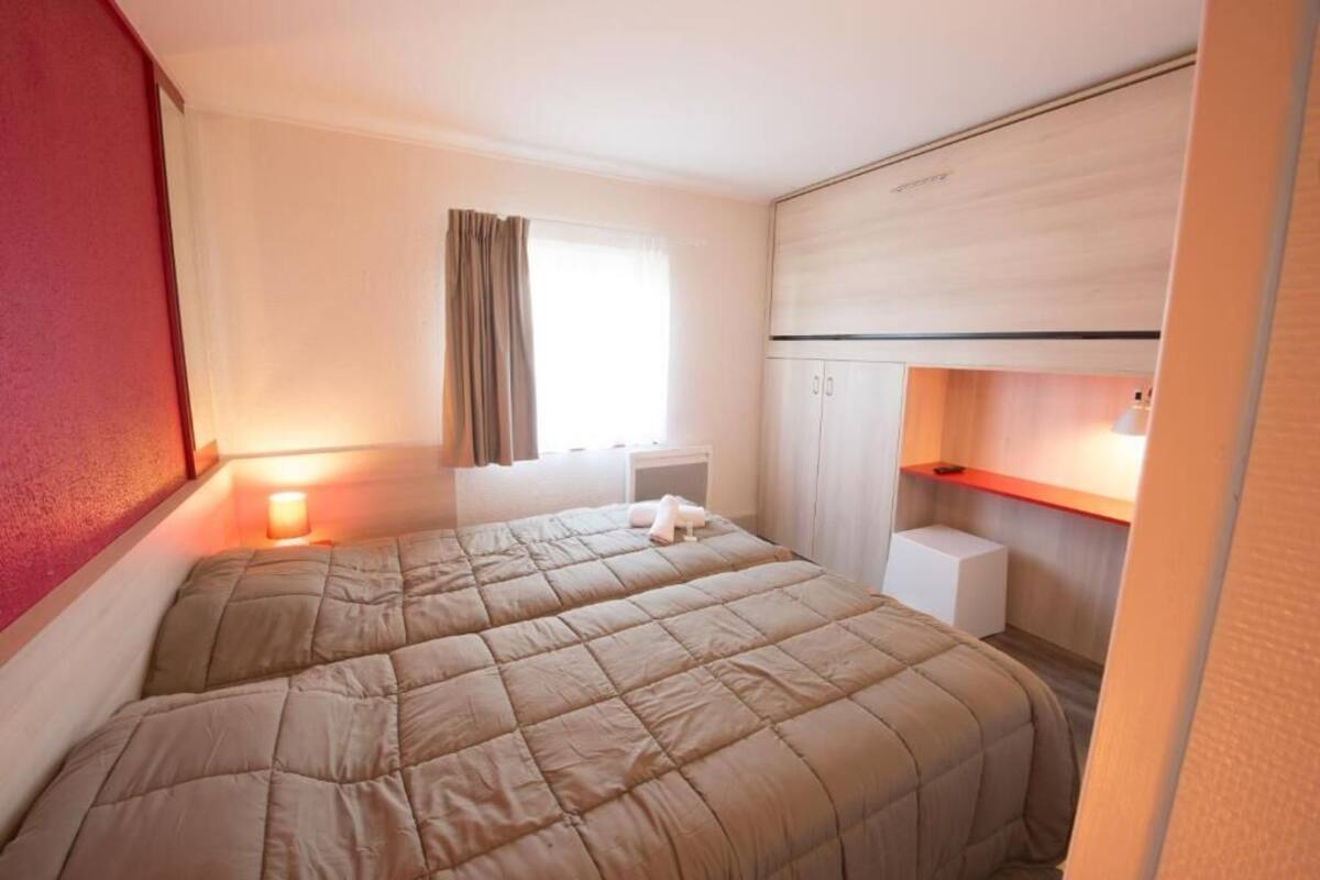 Een slaapkamer met een bed, nachtkastjes, een raam met gordijnen en een kledingkast.
