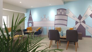 A modern living room with a cityscape mural, a sofa, two armchairs, a coffee table, and a potted plant. - VVF Blériot-Plage (Sangatte)