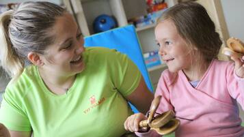 Donna con una maglietta verde e bambino con una maglietta rosa seduti a un tavolo.