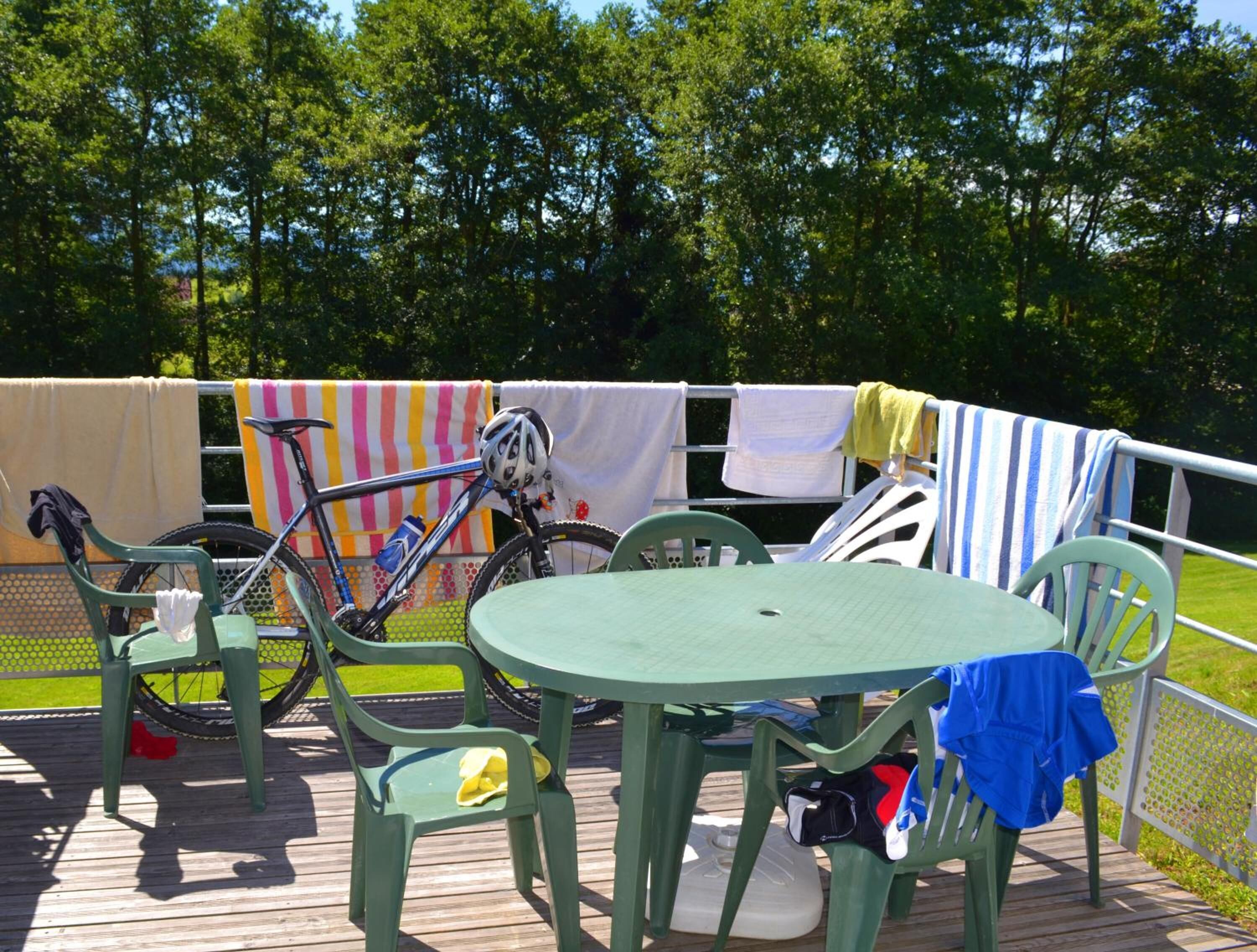 A deck with a table and chairs, a bicycle, and a clothesline with towels.