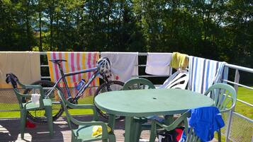 A deck with a table and chairs, a bicycle, and a clothesline with towels.