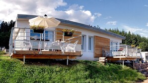 A modern house with a balcony, outdoor seating, and a wooden deck.