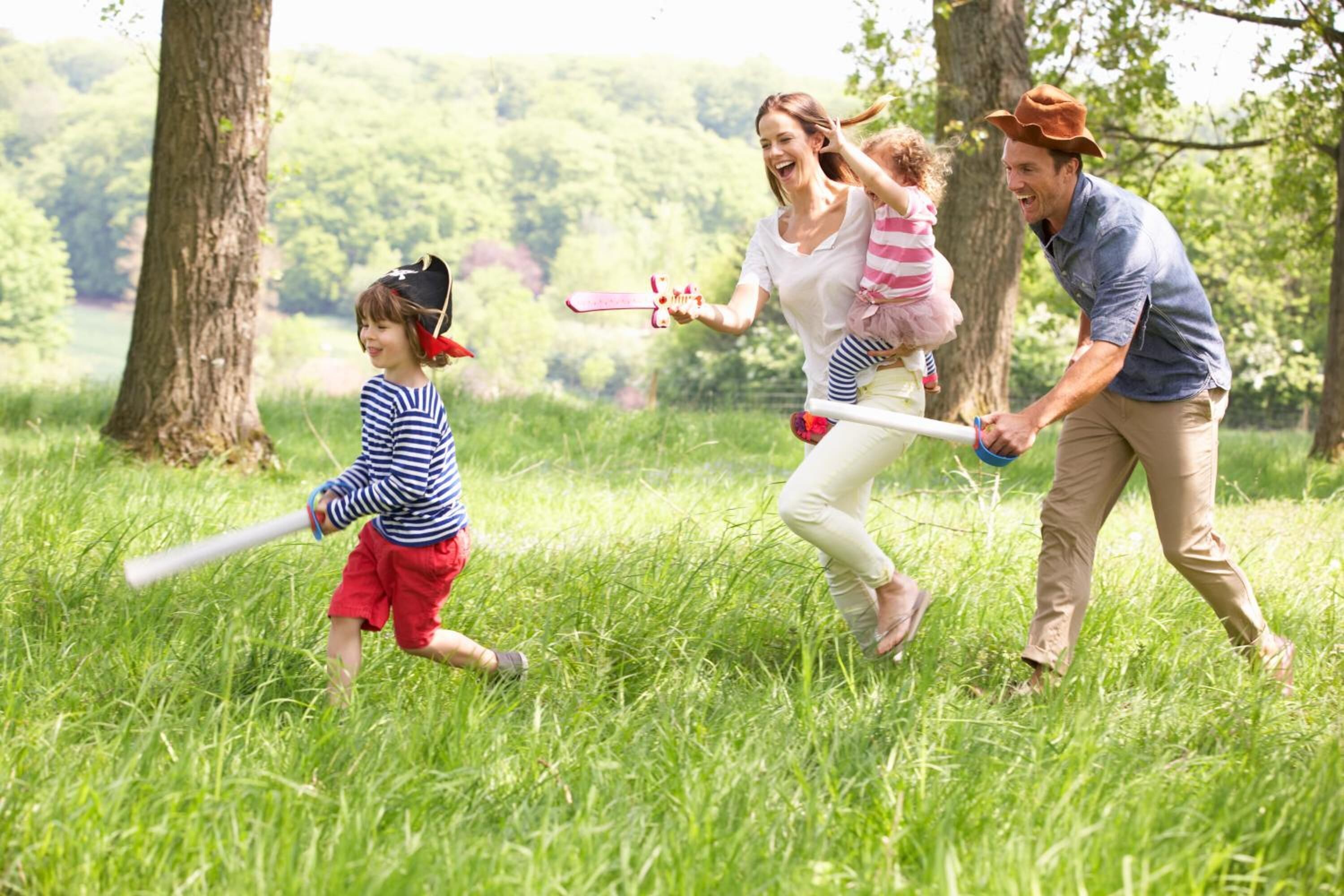 A family in a grassy field with trees and a lake in the background.