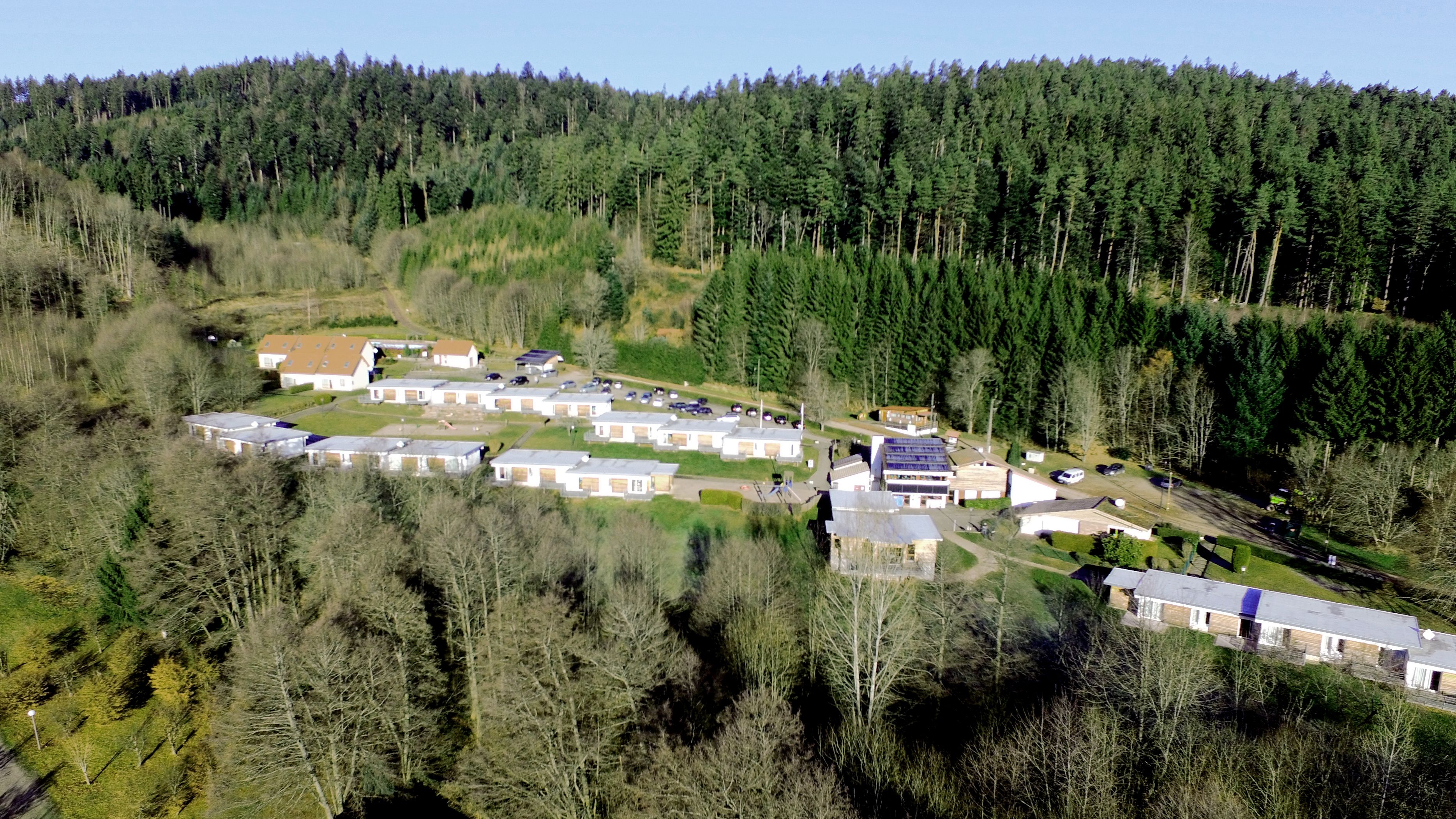 Ein Luftbild eines Wohngebiets mit mehreren eingeschossigen Häusern, umgeben von dichtem Wald.