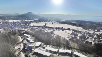 An aerial view of a small town with houses, a large open field, and mountains in the background.