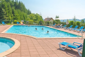 Una piscina al aire libre, sombrillas, sillones reclinables de piscina