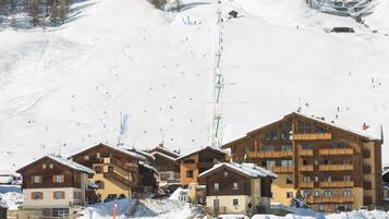 A ski resort with wooden buildings, ski lifts, and a snowy landscape.
