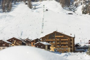 Un centro de esquí con edificios de madera, un telesilla y una pista nevada.