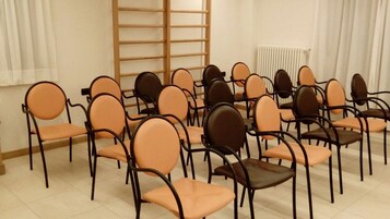 A room with multiple chairs arranged in rows, a wooden ladder, and a radiator.
