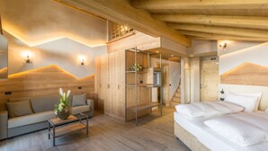 A modern hotel room with a wooden ceiling, a bed with white linens, a sofa, and a small table. - Hotel Amerikan (Livigno)