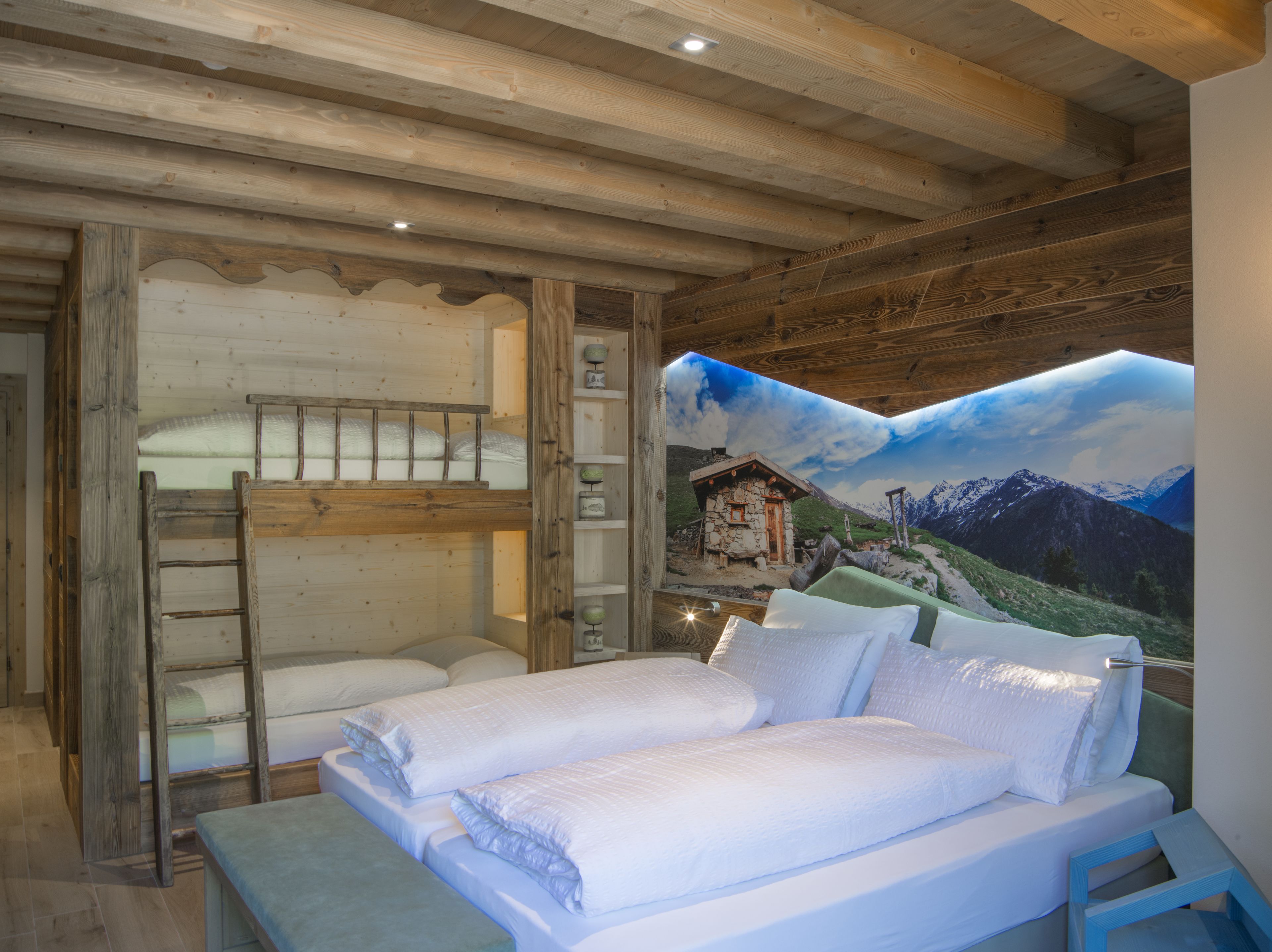 A bedroom with a bunk bed, a ladder, and a mural of a mountain landscape.