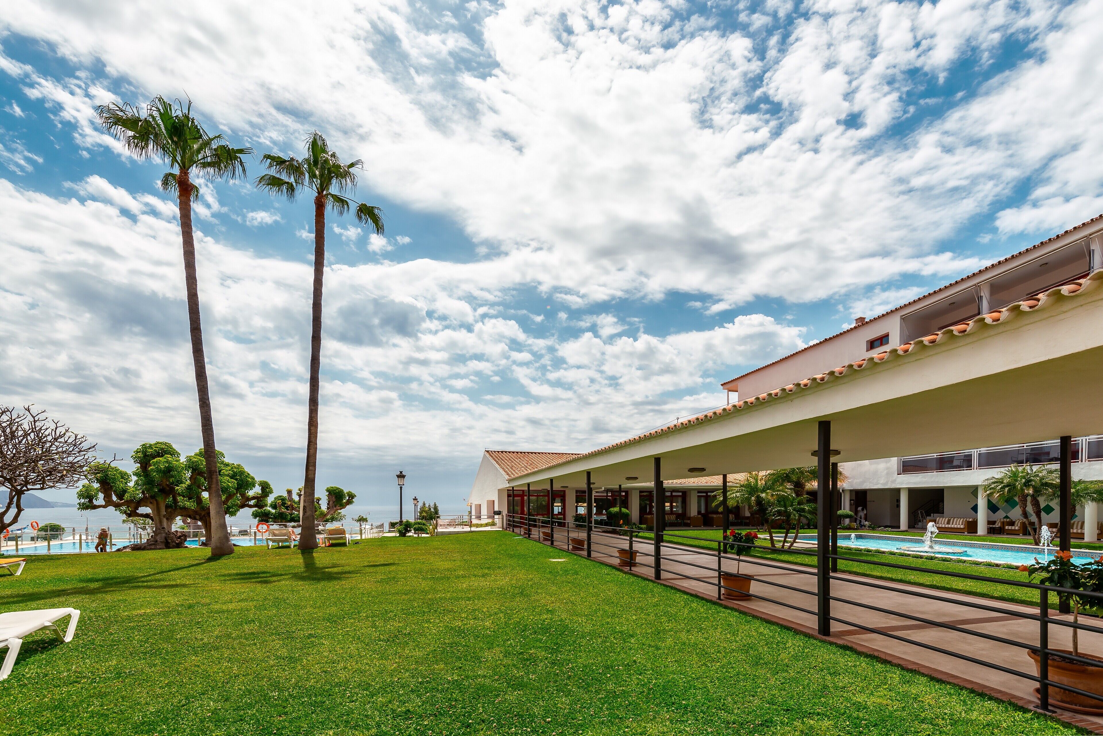 Un hotel con piscina, palmeras y cielo despejado.