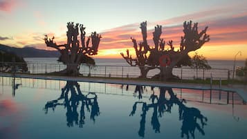 Una piscina al aire libre de temporada, sombrillas, tumbonas